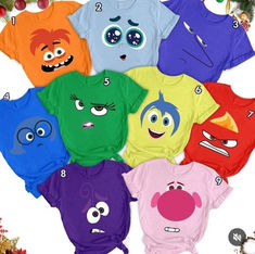 a group of t - shirts with faces on them sitting next to each other in front of a christmas tree