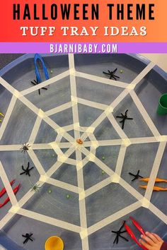 a spider web made out of paper and scissors on a tray with text overlay that says halloween theme tuff tray ideas