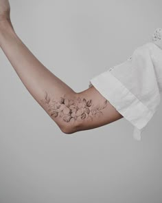 a woman's arm with flowers on it and a white shirt over her shoulder