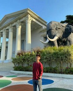 a man is standing in front of an elephant statue at the entrance to a building