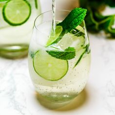 a glass filled with ice and limeade sitting on top of a white countertop