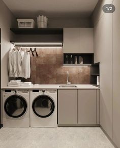 a washer and dryer in a small room next to a counter with clothes hanging on it