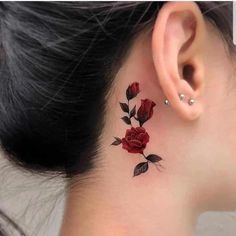 a woman's behind the ear tattoo with red roses