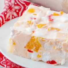 a white plate topped with a piece of cake next to a red and white napkin