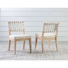 two chairs sitting side by side on top of a rug in front of a white wall