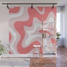 an abstract pink and white wall mural in a living room with wooden flooring, shelving unit and potted plant