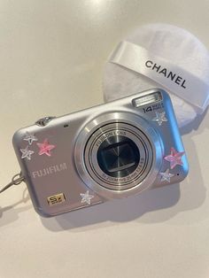 a silver camera sitting on top of a table next to a white hat with stars