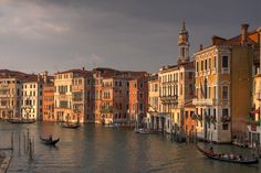 a row of buildings along the water with boats in front of them on a cloudy day