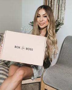 a woman sitting on the floor holding up a box that says, box for the boss