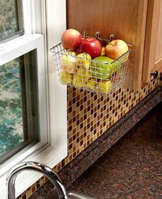 a basket full of fruit sitting on the side of a kitchen sink next to a window