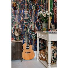 a guitar sitting on top of a table in front of a wall covered with guitars