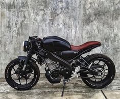 a black and red motorcycle parked in front of a wall