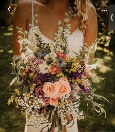 a woman holding a bouquet of flowers in her hands and wearing a wedding dress with an open back