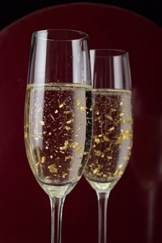 two wine glasses filled with champagne and gold flakes