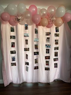 a bunch of balloons that are hanging from a curtain with pictures on it and photos attached to the curtains