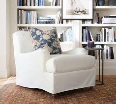 a white chair sitting in front of a bookshelf filled with lots of books