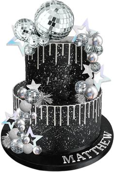 a black and white cake with silver decorations on it's top, surrounded by stars