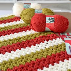 three balls of yarn sitting on top of a crocheted blanket next to each other