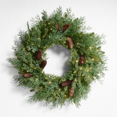 a christmas wreath with pine cones and lights on the front is displayed against a white background