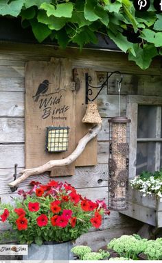 a bird house with red flowers in the foreground