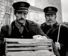 two men dressed in uniforms sitting next to each other on a wooden bench and looking at the camera