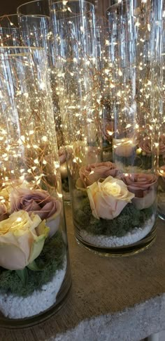 some glass vases with flowers and lights in them