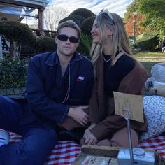 a man and woman sitting on a picnic blanket