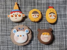 four decorated cookies sitting on top of a gray cloth covered table next to each other