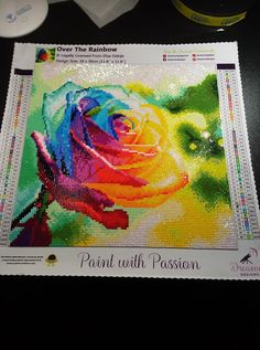 a cross stitch pattern with a colorful rose on the front and side, along with other sewing supplies