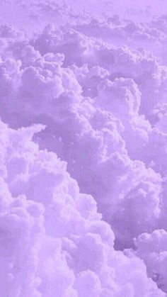 the sky is filled with fluffy clouds and purple hues, as seen from an airplane window