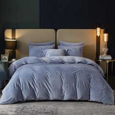 a bed with blue comforter and pillows in a room next to a lamp on a table