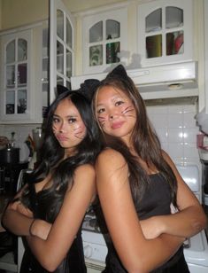 two young women in black cats costumes posing for the camera with their arms around each other