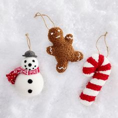 three ornaments made to look like snowmen and gingerbreads are hanging on the snow