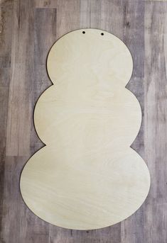 a wooden snowman sitting on top of a hard wood floor next to a wall