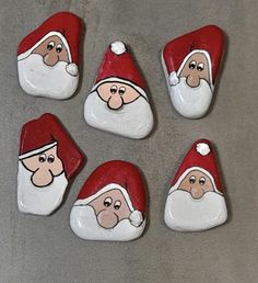 six santa clause rocks sitting on top of a gray surface with white and red decorations