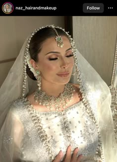 a woman in a wedding dress with pearls on her head and veil over her face