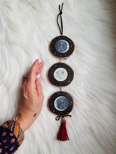 a hand is reaching for three small clocks on a white furnishing area with tassels