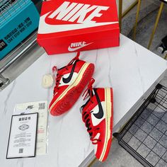 a pair of red nike sneakers sitting on top of a table next to a box