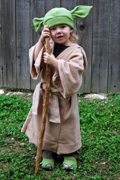 a young child dressed as yoda holding a stick