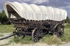 an old covered wagon sitting in the grass