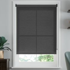 a room with a window covered in gray blinds and a potted plant next to it