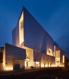 the building is lit up at night with bright lights on its windows and side walls