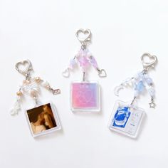 three keychains with pictures attached to them on a white surface, one has a baby's photo and the other has an angel