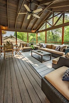 a covered porch with couches, tables and chairs on top of the wooden floor