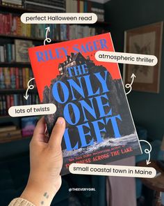 someone holding up a copy of the only one left novel in front of a bookshelf