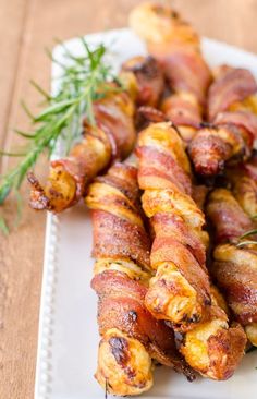 bacon wrapped in bacon and garnished with fresh herbs on a white platter