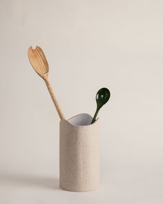 two wooden spoons sticking out of a concrete cup with a green spatula in it