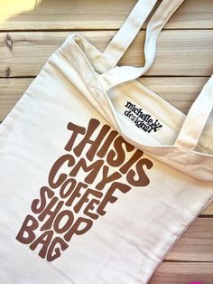 **"This is My Coffee Shop Bag" Canvas Tote Bag - Coffee Quote Design** This tote is more than just a bag--it's an expression of your unique personality and style. It's designed to be both stylish and practical, perfect for everyday use. Here's what makes it special: **Product Details - **Size 15" x 13" - Spacious enough for all your daily needs. - **Handle Length 12" - Comfortable for carrying by hand or over your shoulder. - **Material Canvas - Durable and eco-friendly. - **One-of-a-Kind** **Why You'll Love This Tote - **Eco-Friendly & Reusable Ditch single-use bags for this eco-conscious alternative, perfect for sustainable living. - **Trendy & Stylish Whether you're shopping, going on a day trip, or just carrying your daily essentials, this tote is perfect for any occasion. Michelle of Coffee Tote Bag Design, Simple Tote Bag Design, Coffee Tote Bag, Craft Market Display, Shop Bag, Simple Tote, Coffee Painting, Coffee Club, Quote Design