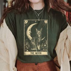 Tarot Card Crescent Moon Cat Shirt The Moon Tarot Card Shirt, Funny Cat Shirt, Celestial Shirt, Mystic Mom Shirt, Cat And Moon Shirt 📣 INFORMATION * All shirts are UNISEX * 100% Airlume combed and ringspun cotton (fiber content may vary for different colors) * Wash and dry normally (on cool for best results) 👕 SIZING * For an oversized fit, select two or three sizes up from your normal size * Model is wearing size L * Sizing runs true to size * Most women find their typical size works best, si Tarot Card Shirt, Moon Tarot Card, Celestial Shirt, Cat And Moon, The Moon Tarot Card, The Moon Tarot, Moon Cat, Moon Shirt, Cat Shirt