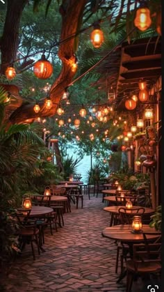 an outdoor dining area with lanterns hanging from the ceiling and tables set up for dinner